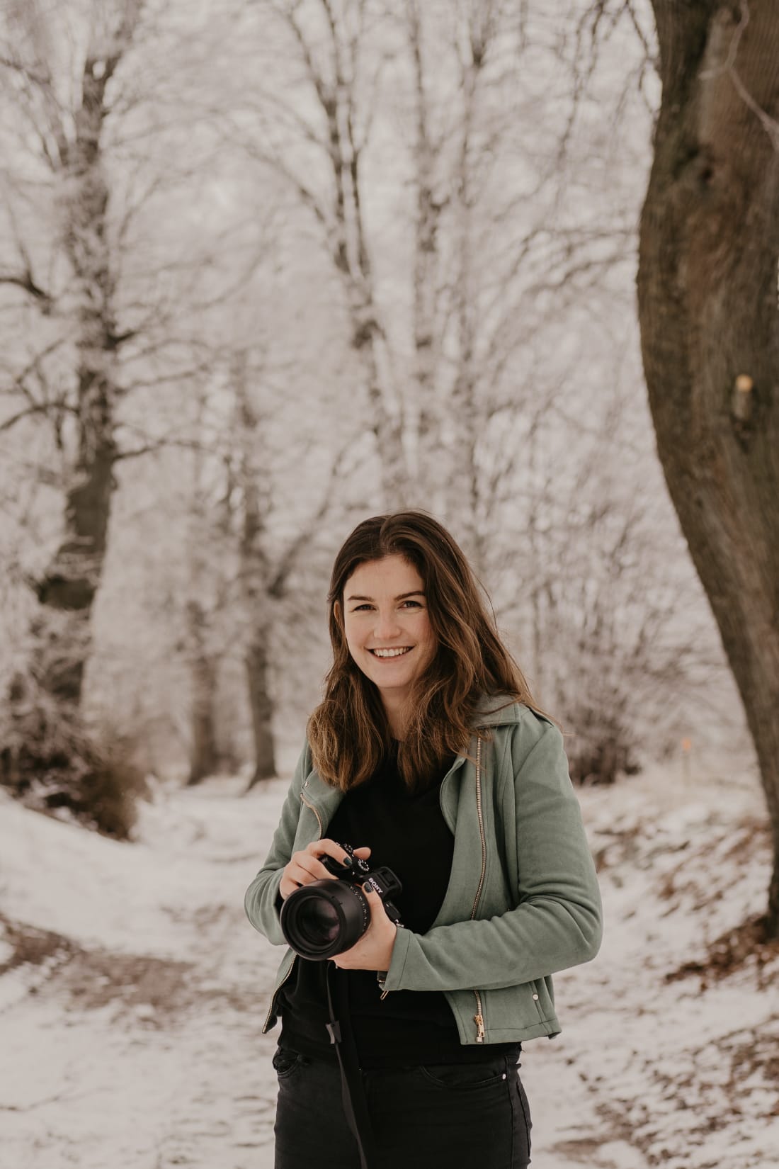 Fotograf in Grömitz hält Kamera und lächelt im Schnee